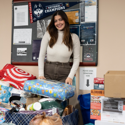Adriana Victoria Lopez, Graduate Assistant, smiling next to donations